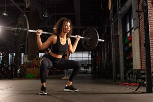 A person performing a squat with a barbell in a gym