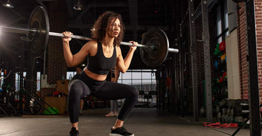 A person performing a squat with a barbell in a gym