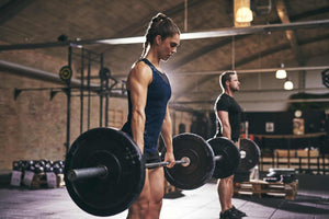 Woman and man holding barbells loaded with black weight plates