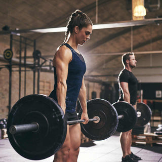 Woman and man holding barbells loaded with black weight plates