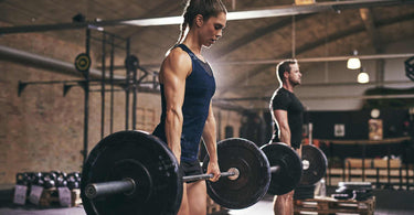 Woman and man holding barbells loaded with black weight plates